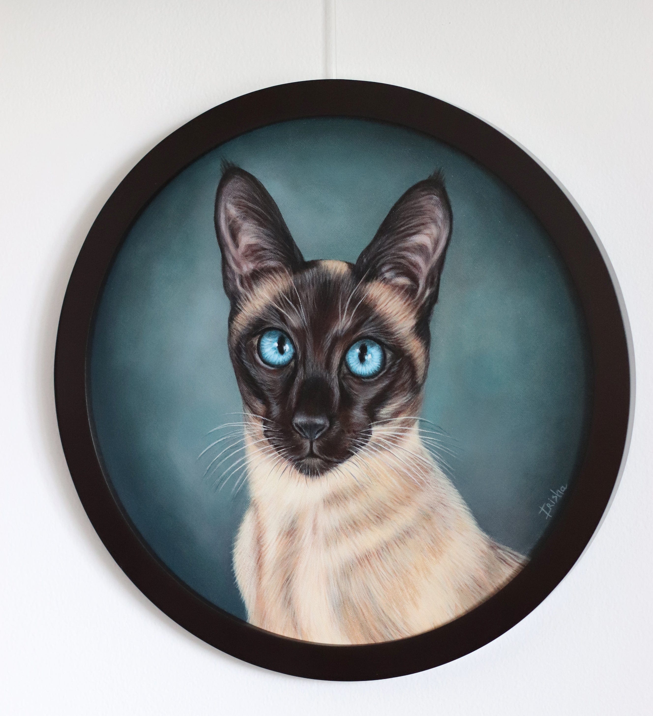 Framed artwork of a Siamese cat with blue eyes on a white wall.