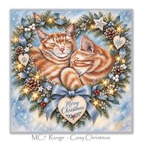 Christmas card for cat lovers with two sleeping ginger kittens surrounded by Christmas greenery and blue ribbons