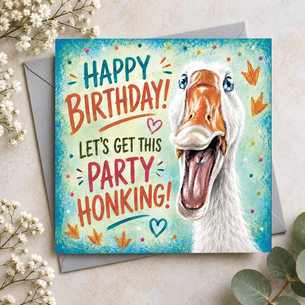 Funny goose birthday card featuring a white goose with bright blue eyes and wide-open beak with Let's Get This Party Honking message.