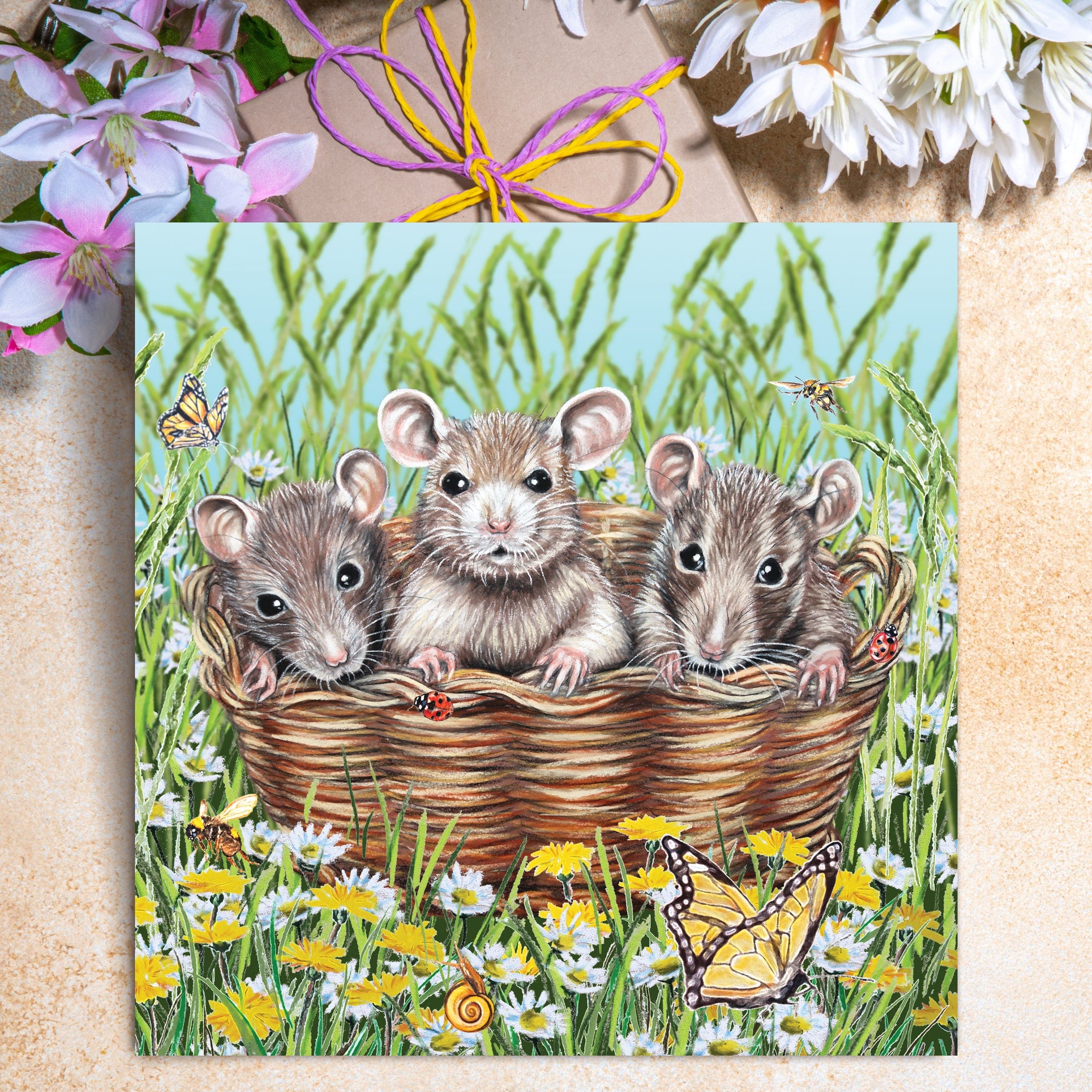 Cute mice greeting card featuring three little mice sitting in a basket surrounded by daisies, dandelions, butterflies, and bees.