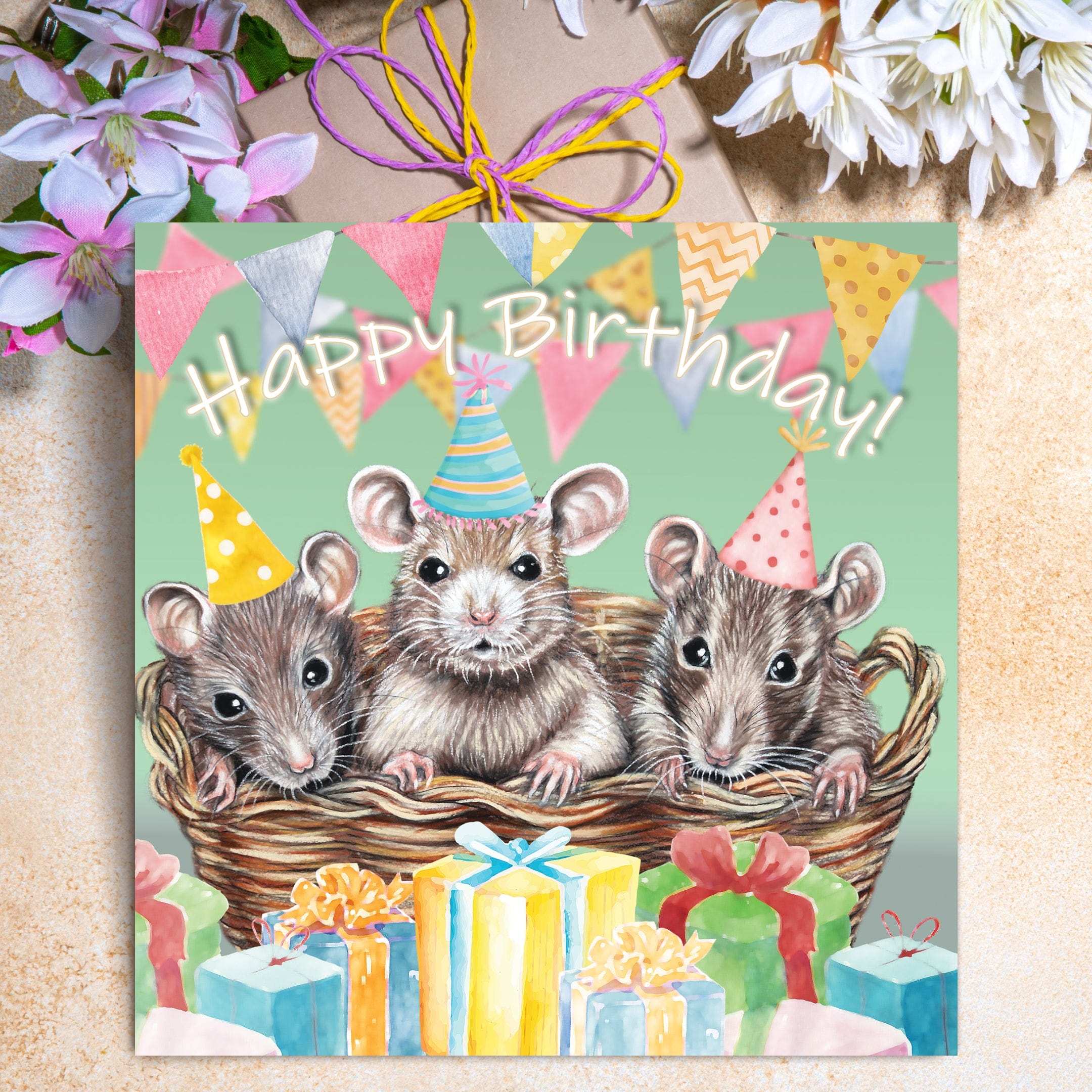 Cute mouse birthday card featuring three mice in a basket wearing party hats, surrounded by presents and colourful bunting with the words Happy Birthday.