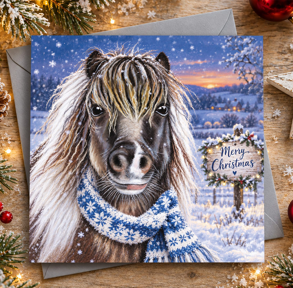 Shetland Pony Christmas card featuring a shaggy brown pony wearing a blue snowflake scarf in the snow
